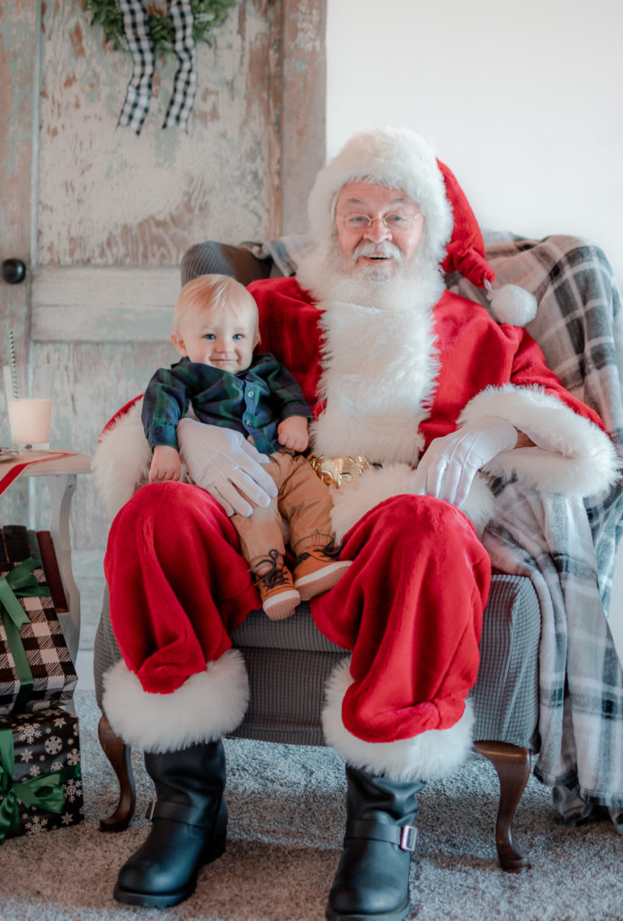 Santa Claus sitting in chair with a baby boy during 2020 Santa Mini photo session