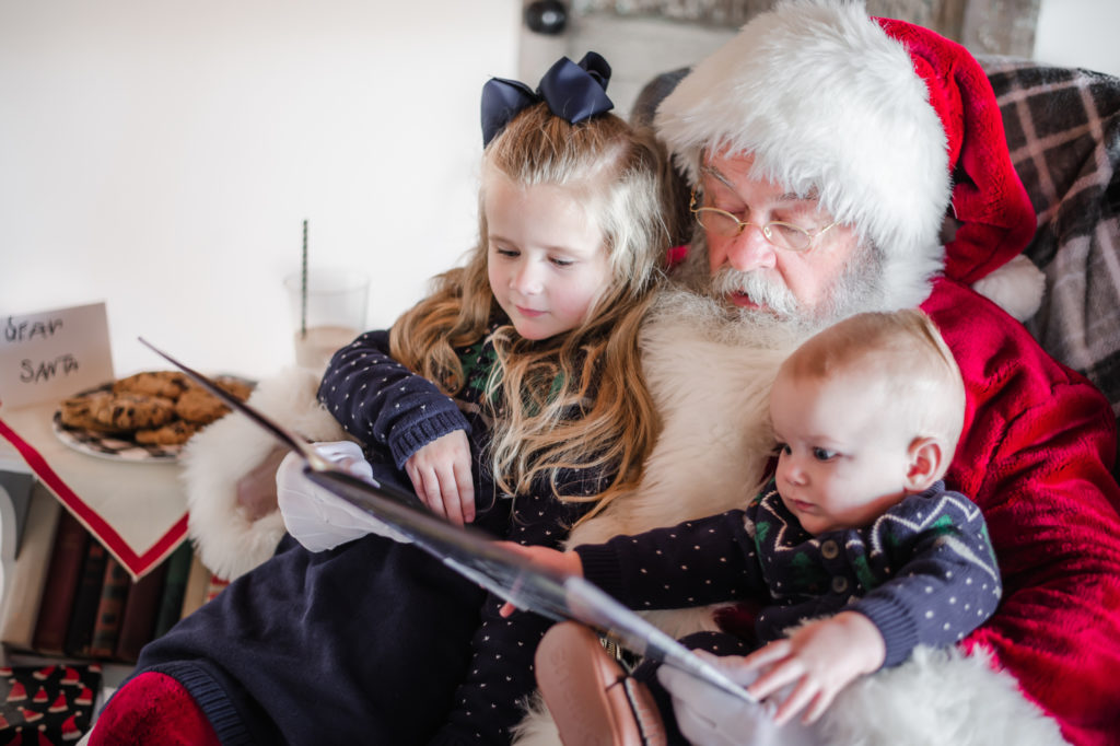 Santa Claus reading a story to siblings during 2020 Santa Mini photo session