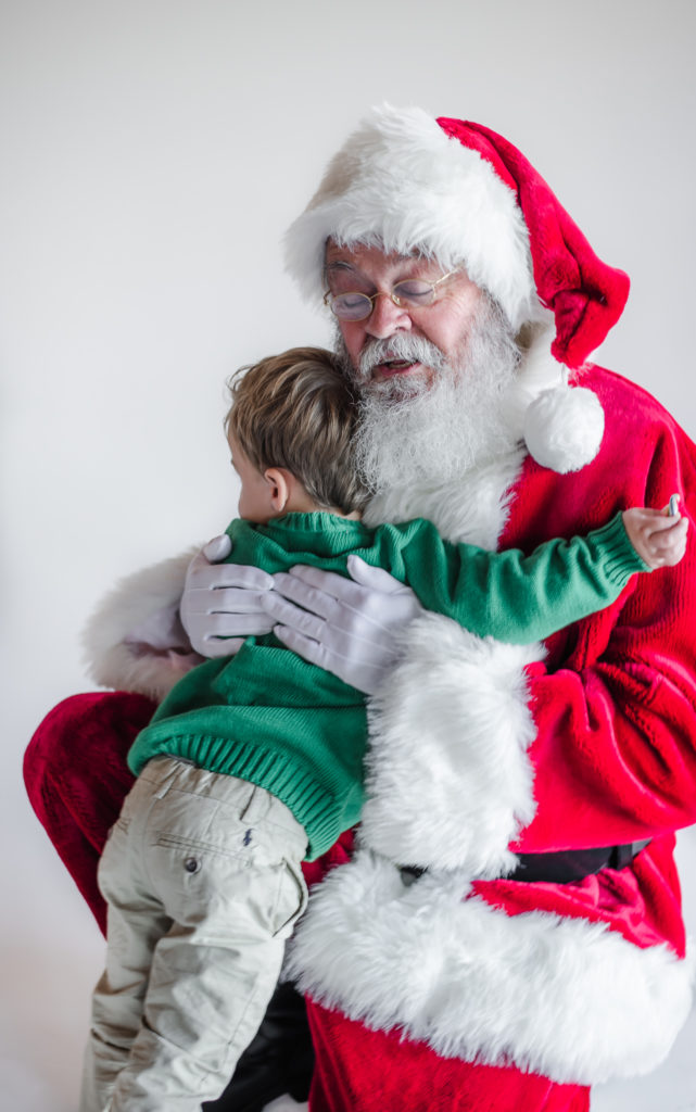 Santa Claus hugging young boy during 2020 Santa Mini photo session