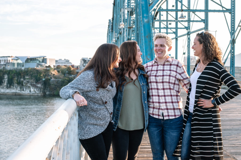 Friends standing on bridge,  laughing and having fun during a photo session