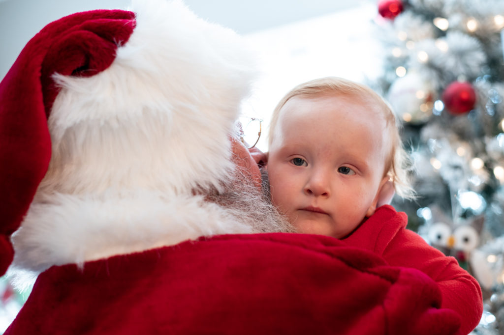 Santa whispering into baby's ear during a “Home for the Holidays” Santa Session