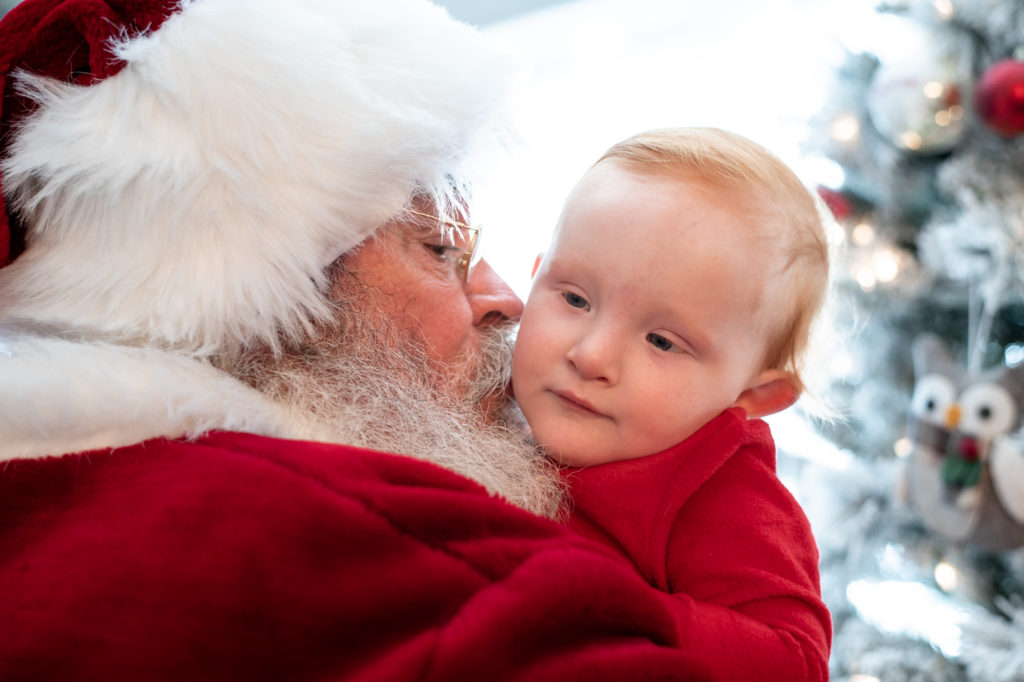 Santa kissing baby on cheek during a “Home for the Holidays” Santa Session