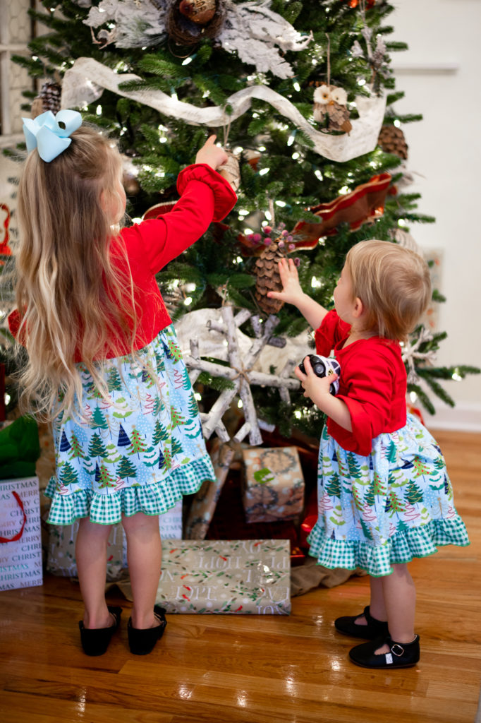 Two young sisters in front of Christmas tree 