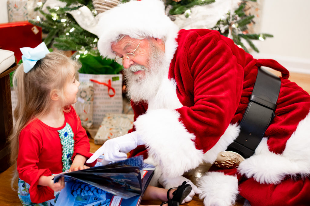 Santa reading a book with young girl 