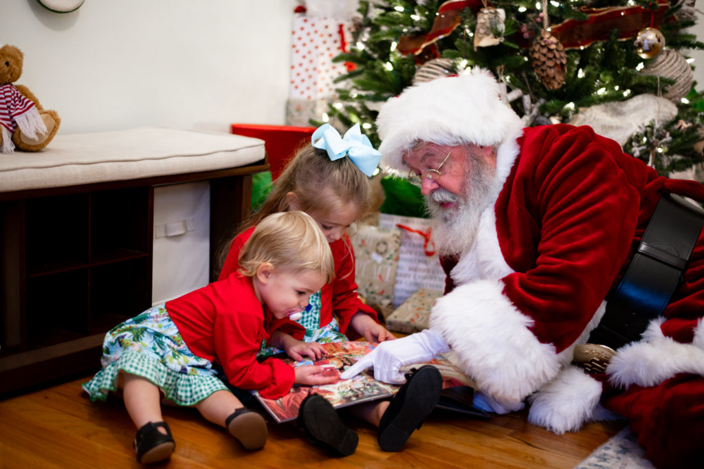 Santa reading a book with sisters during "Home for the Holidays" Santa session