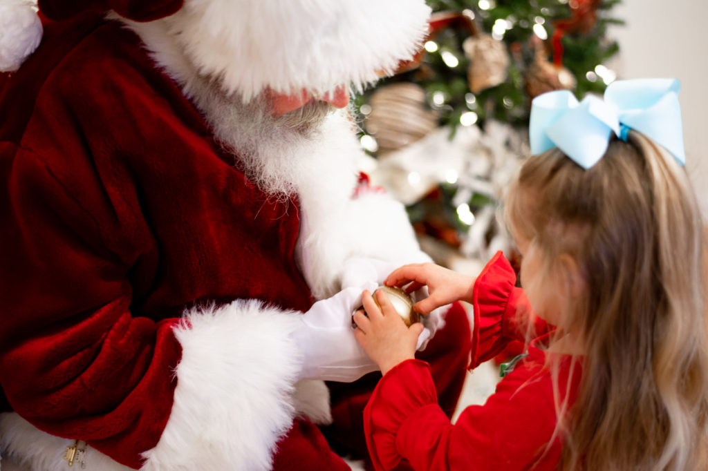 Santa giving young girl a toy with candy 