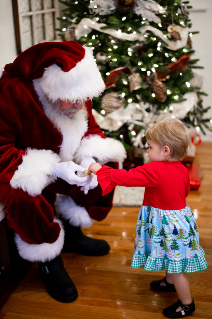 Little girl handing candy to Santa Claus 